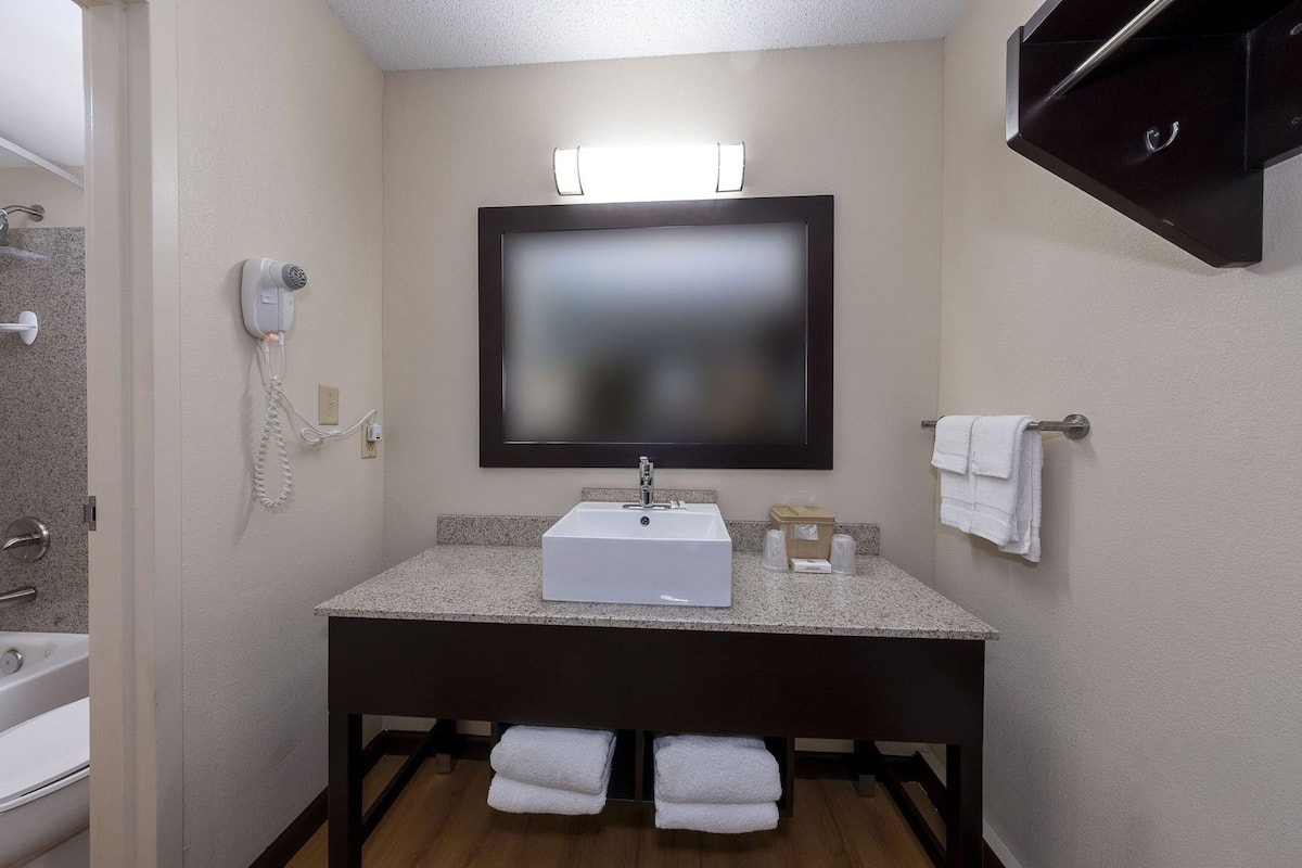 Une salle de bain équipée d’un lavabo, d’un miroir, d’un porte-serviettes et d’un sèche-cheveux.