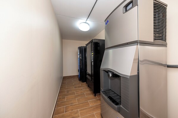 A corridor with a tiled floor, a ceiling light, and vending machines. - Red Roof Inn PLUS+ Huntsville - Madison (Madison)