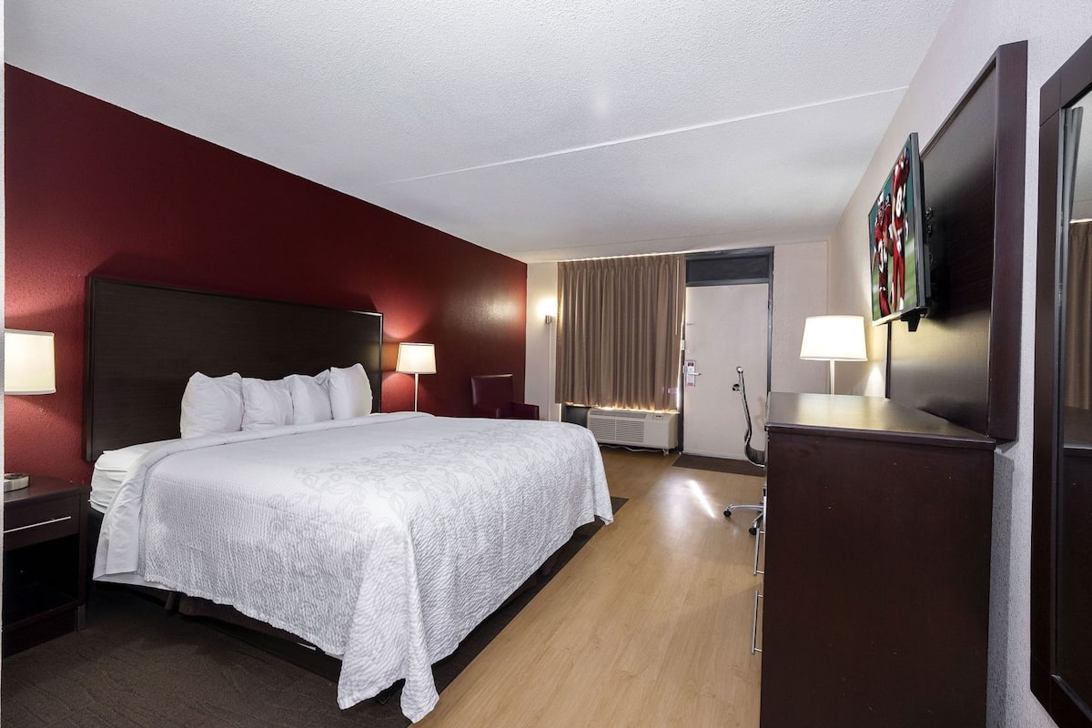 Une chambre d’hôtel avec un grand lit, des lampes de chevet, une télévision et un bureau.