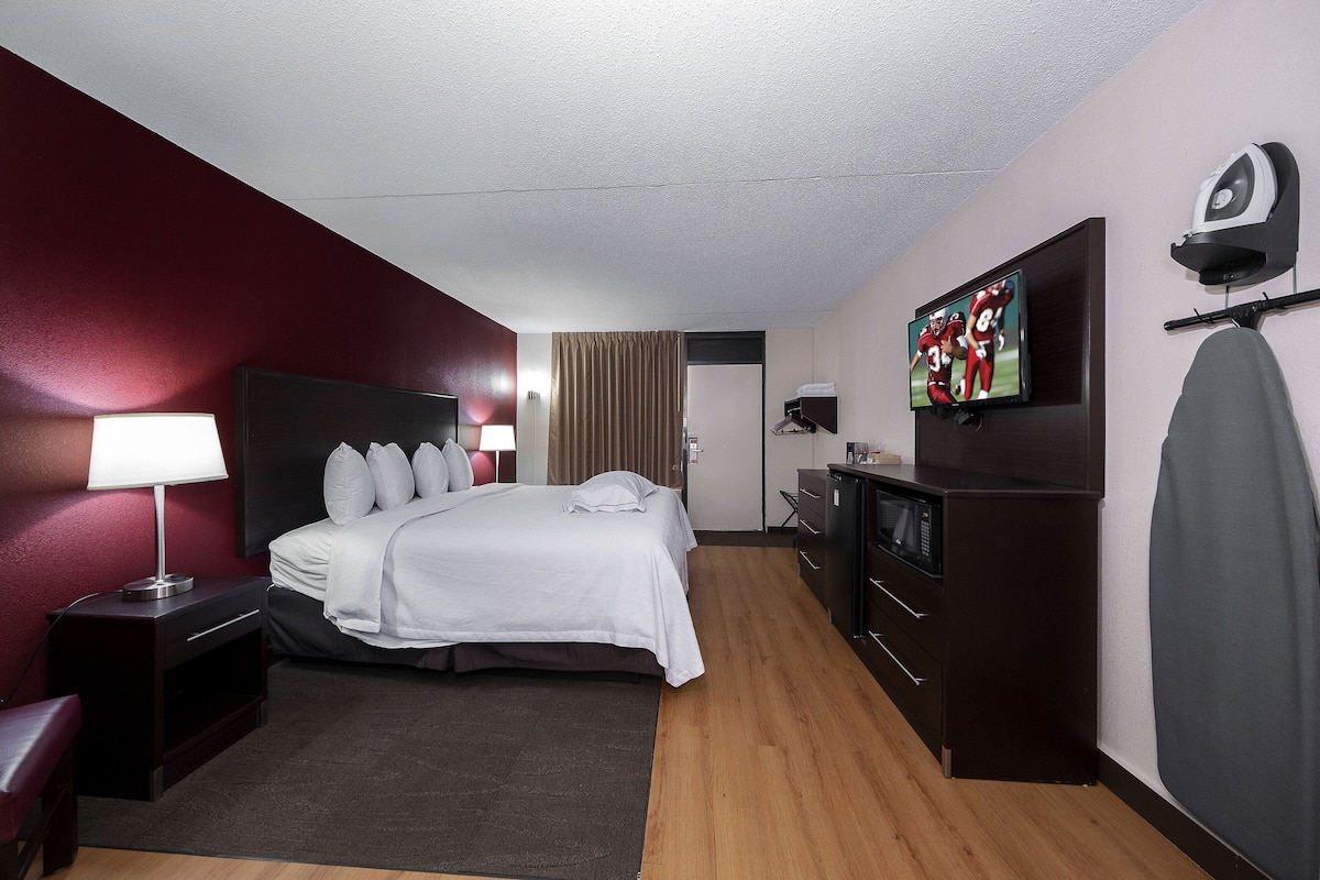 A hotel room with a bed, a desk, a TV, a microwave, and a wardrobe.