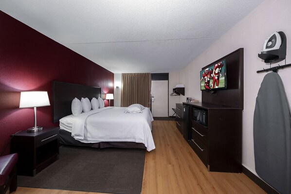 A hotel room with a bed, a desk, a TV, a microwave, and a wardrobe. - Red Roof Inn PLUS+ Huntsville - Madison (Madison)
