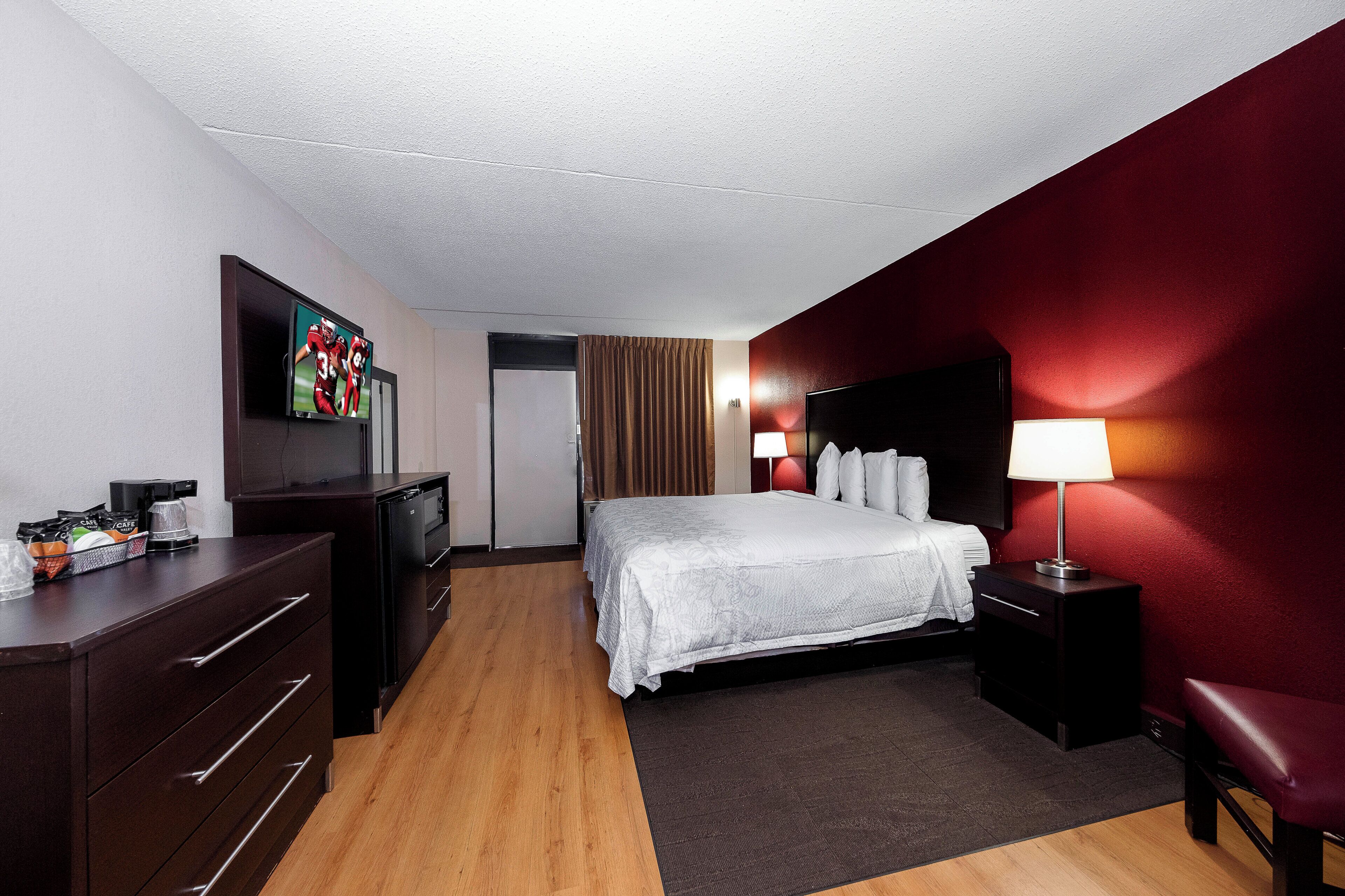A hotel room with a bed, a desk, a television, a coffee maker, and a lamp.
