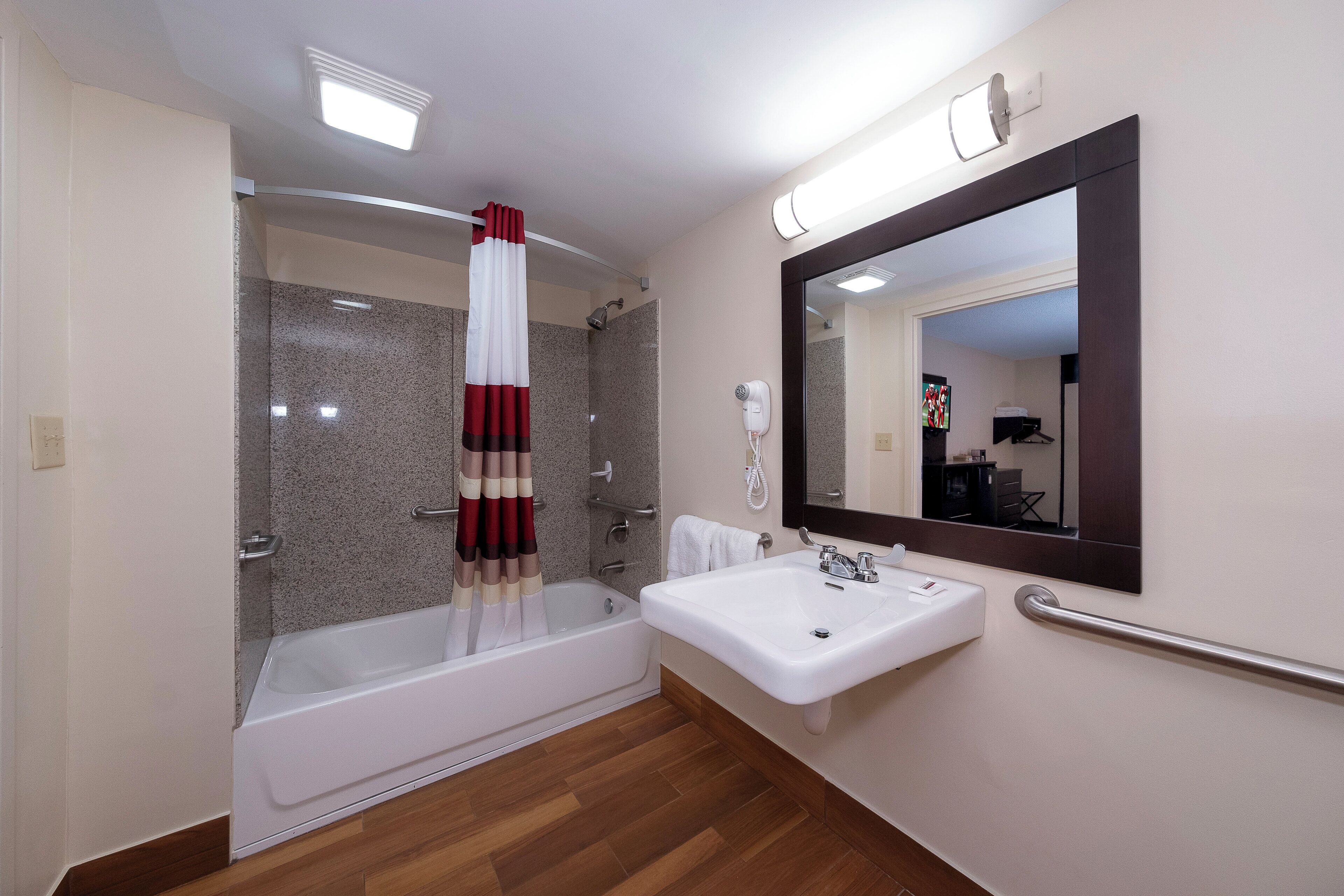 A bathroom with a bathtub, a sink, a mirror, and a shower.