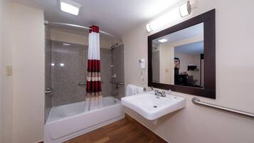 A bathroom with a bathtub, a sink, a mirror, and a shower.