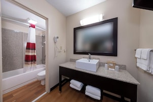 Un baño con ducha, inodoro, lavabo y un espejo grande.