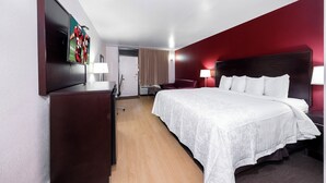 Habitació d'hotel amb un llit gran, una taula de treball, una cadira, un televisor i una porta.
