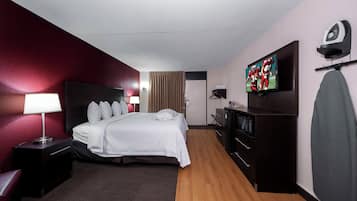 Ein Hotelzimmer mit Bett, Nachttischlampe, Fernseher, Kommode und Mikrowelle.