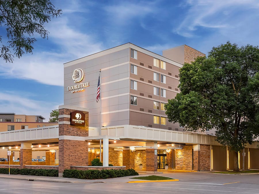 A hotel with a prominent sign, a flag, and a well-lit entrance.