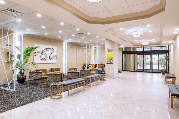 A spacious lobby with seating areas, a reception desk, and a glass door entrance.