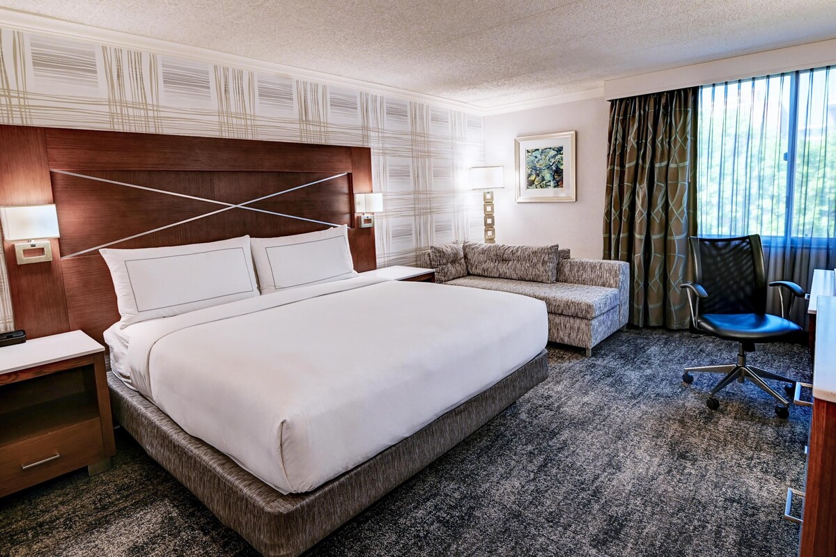 A hotel room with a large bed, a sofa, a desk, and a chair.