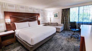 A hotel room with a large bed, a sofa, a desk, and a chair.