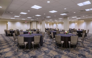 A conference room with multiple tables and chairs, arranged in a grid pattern.