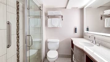 A modern bathroom with a glass shower enclosure, a toilet, a sink with a mirror, and a towel rack.
