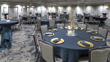 A conference room with round tables, chairs, and a central pillar.