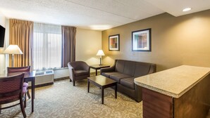 Une chambre d’hôtel équipée d’un canapé, d’un fauteuil, d’une petite table et d’un coin cuisine.