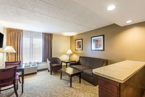 Habitación de hotel con sofá, sillón, una mesita y una zona de kitchenette.