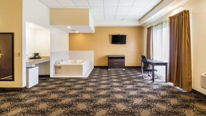 Une chambre d’hôtel équipée d’une baignoire, d’un bureau, d’une chaise, d’une télévision et d’un tapis à motifs.