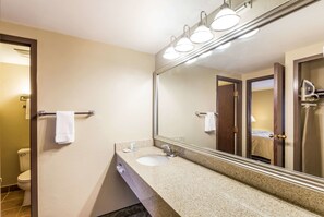 Un baño con lavamanos, espejo y toallero.