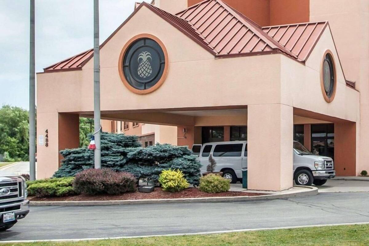 A building with a distinctive pineapple logo, a covered parking area, and a well-maintained landscape.
