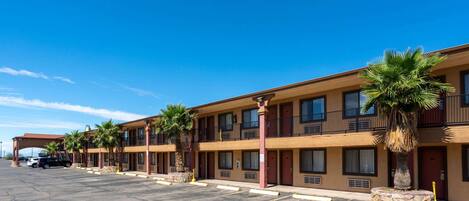 Un motel con varias habitaciones, aparcamiento y palmeras.