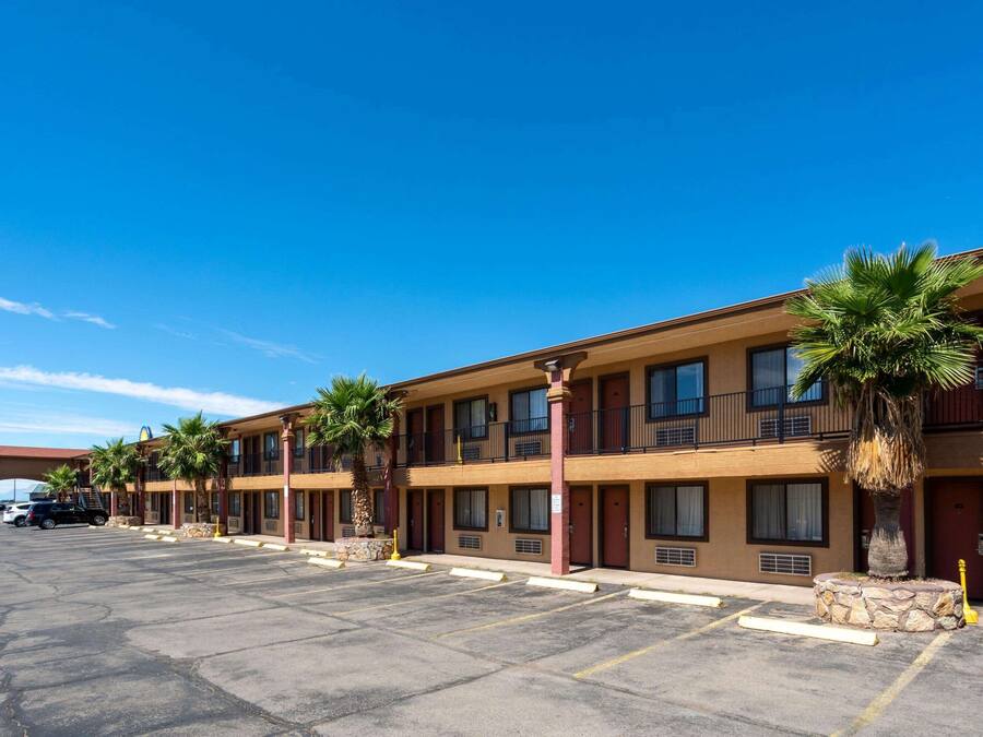 A motel with multiple rooms, a parking lot, and palm trees.