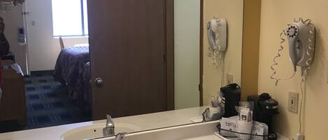Ein Hotelbad mit einem großen Spiegel, zwei Waschbecken, einem Fön und einer Kaffeestation.