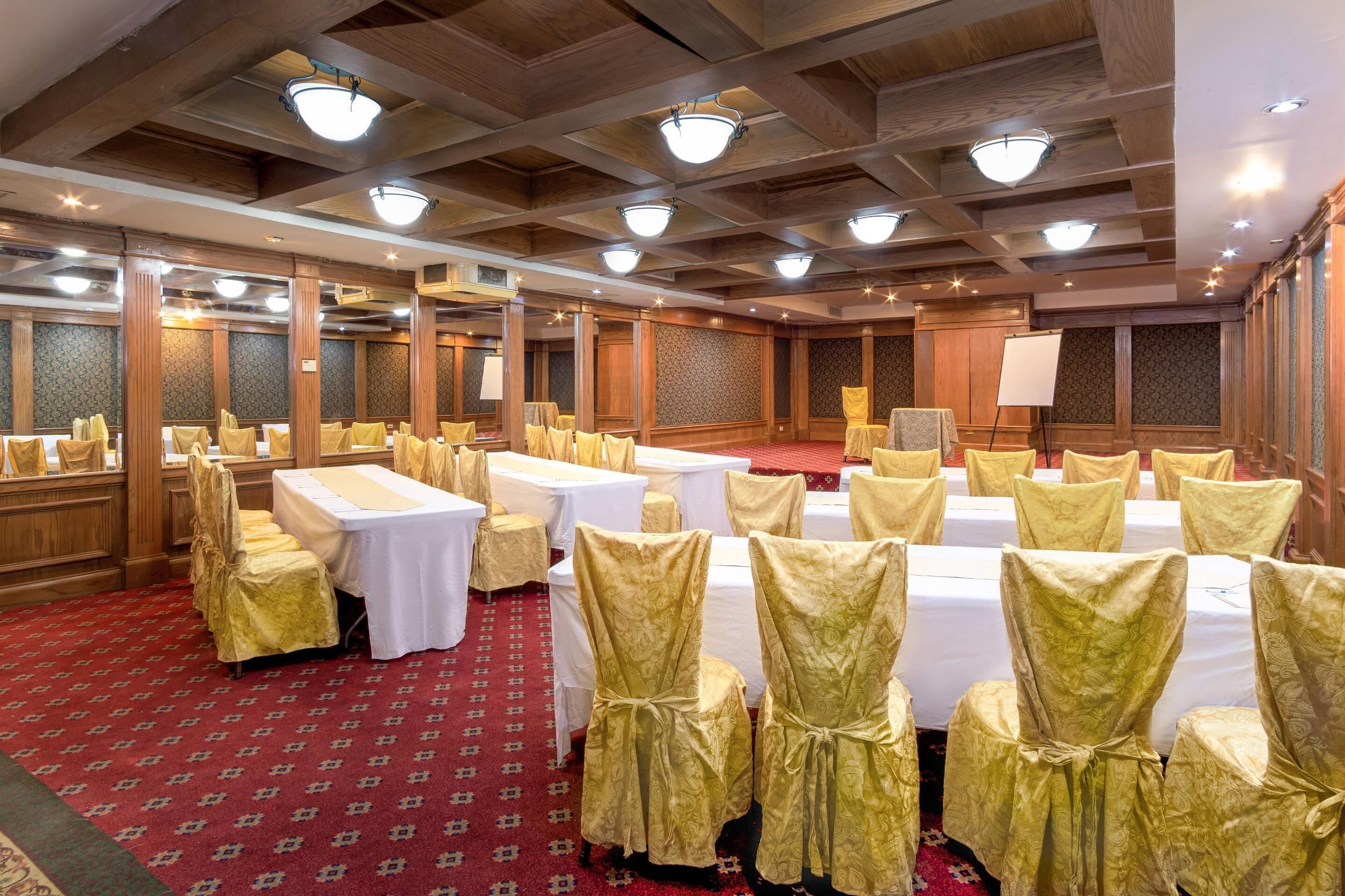 Un salón de banquetes con mesas dispuestas para eventos, paneles de madera y candelabros.
