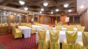 Un salón de banquetes con mesas dispuestas para eventos, paneles de madera y candelabros.