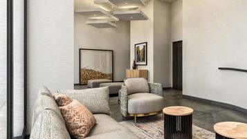 Una sala de estar moderna con un sofá gris, cojines estampados, una mesa de centro de madera y una alfombra.