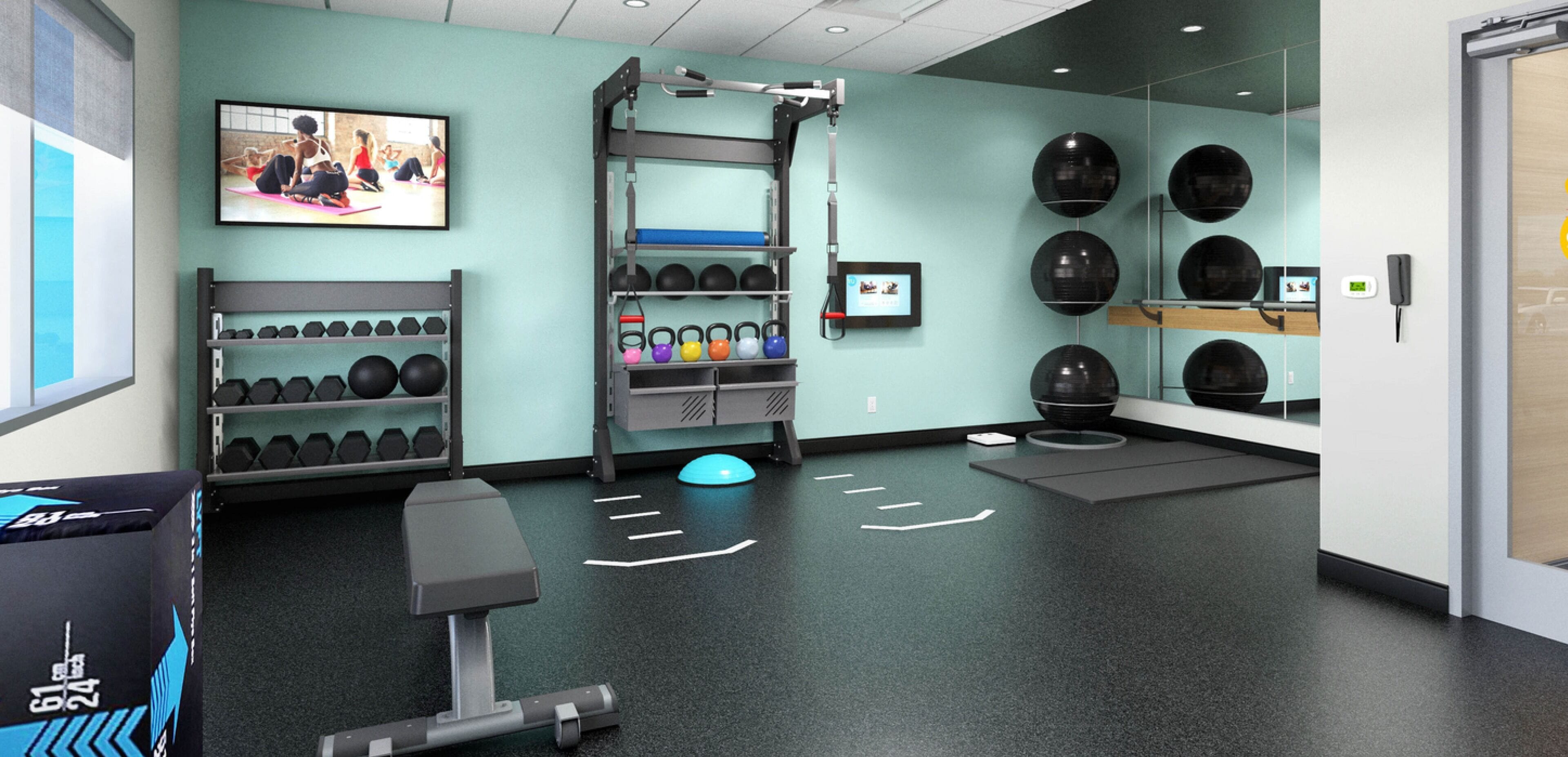 A gym with exercise equipment, a wall-mounted television, and a mirror.