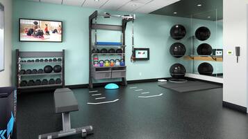 A gym with exercise equipment, a wall-mounted television, and a mirror.