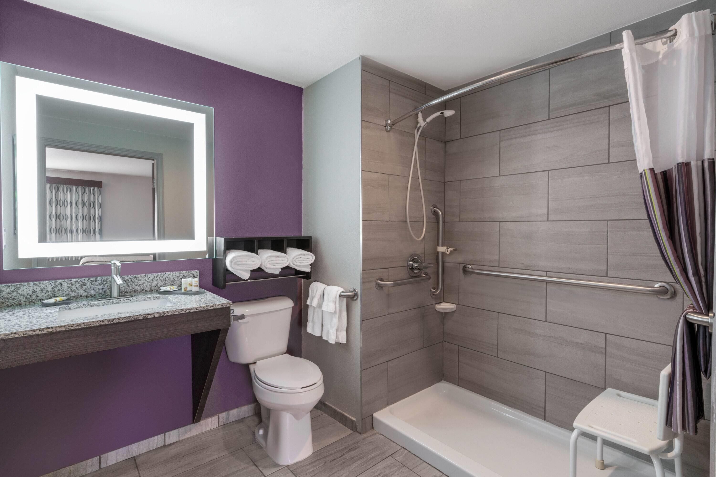 A modern bathroom with a vanity, toilet, shower, and a bathtub.