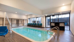 Una piscina interior con vista despejada, una silla azul y un área de descanso con sillas y una barra.