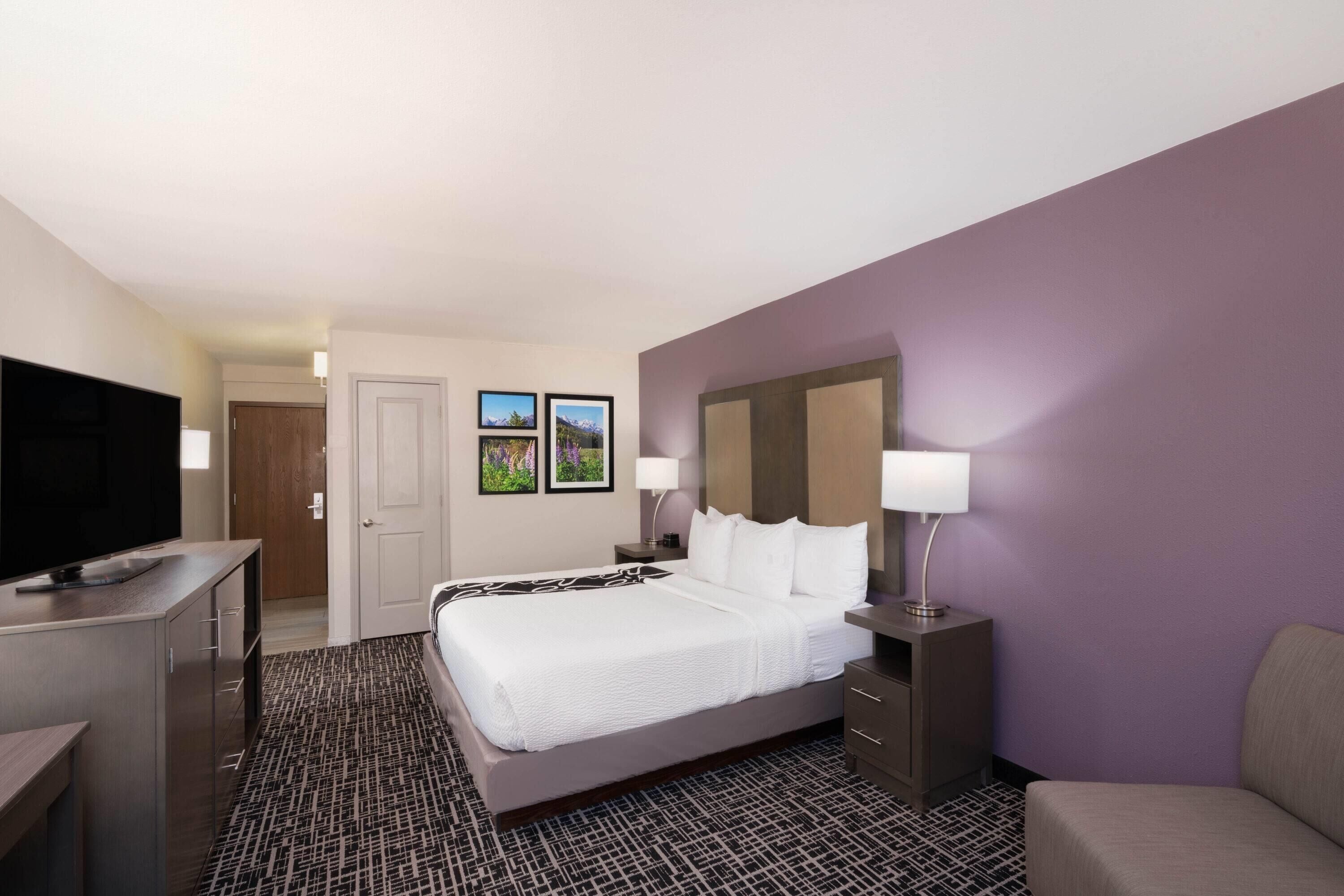 A hotel room with a bed, a TV, a desk, and a chair.
