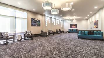 A spacious lobby with a carpeted floor, seating area with sofas and chairs, and artwork on the walls.