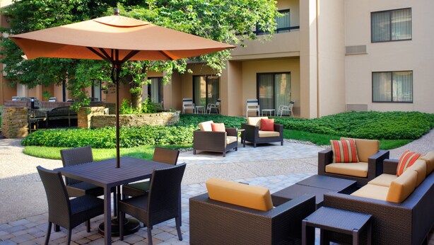 An outdoor patio with wicker furniture, a table, and an umbrella. - Courtyard by Marriott Lexington North (Lexington)