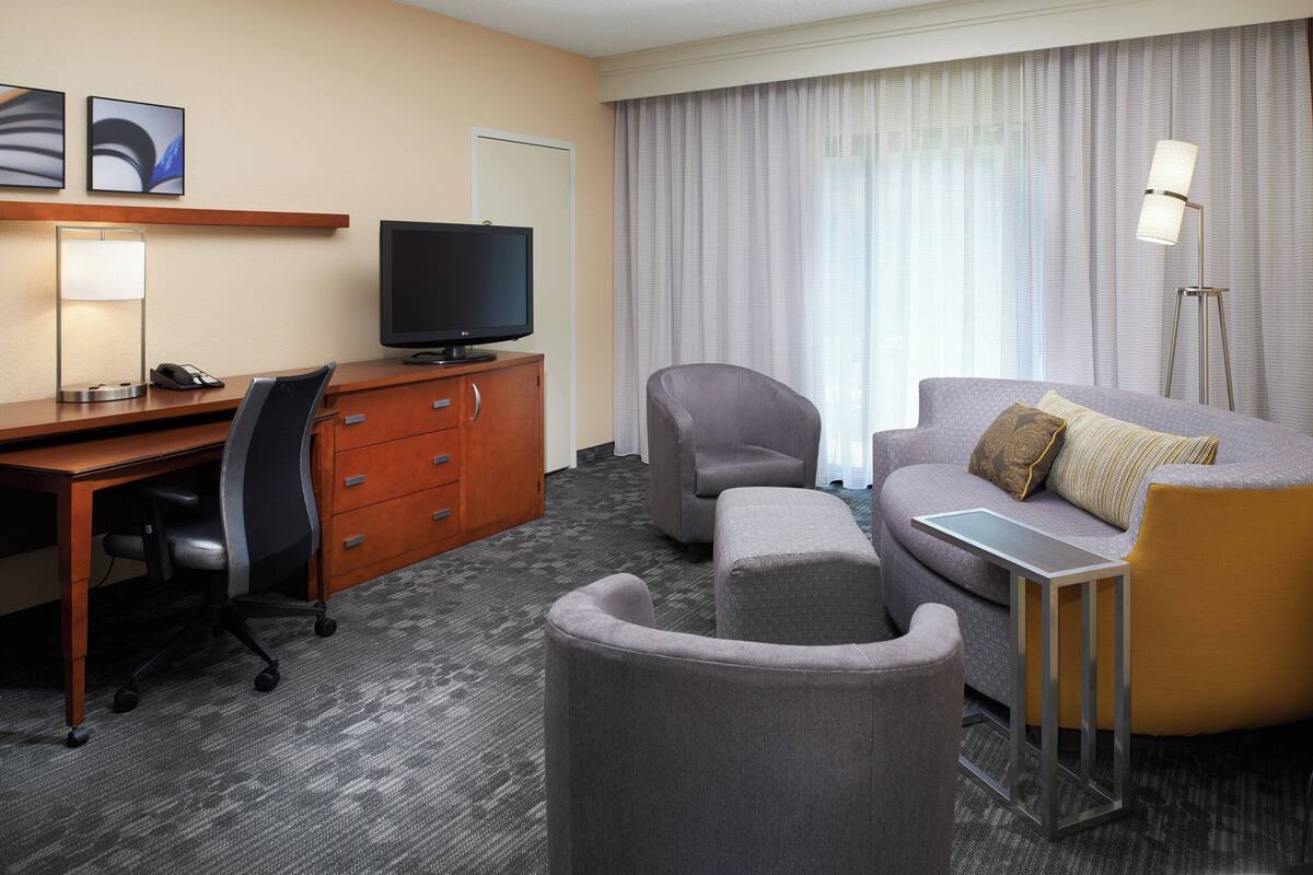 Ein Hotelzimmer mit Schreibtisch, Stuhl, Sofa und Fernseher.