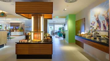 A modern hotel lobby with a central island, a reception desk, and a green accent wall.