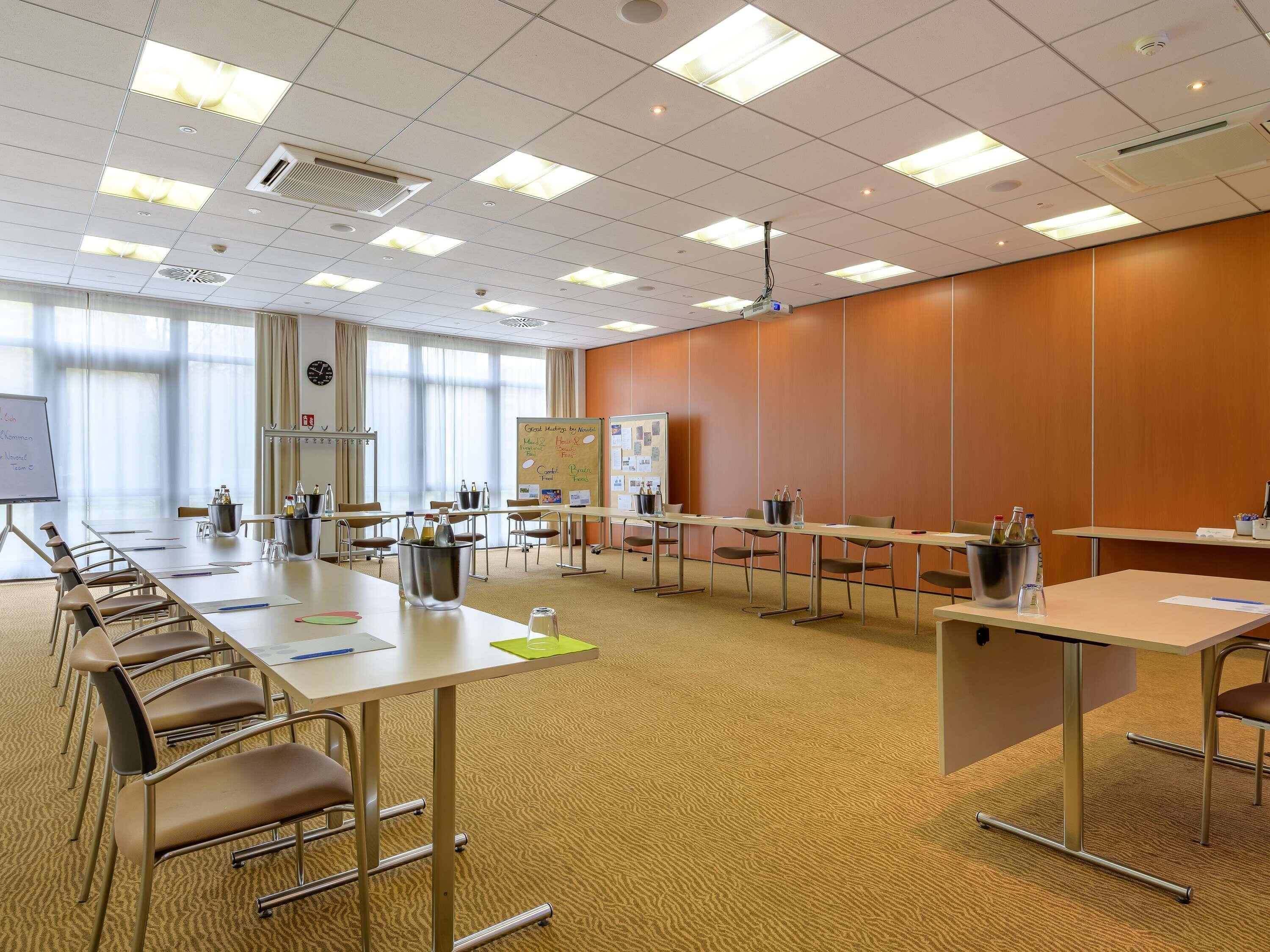 Ett konferensrum med ett långt bord, stolar, en whiteboard och en projektor.