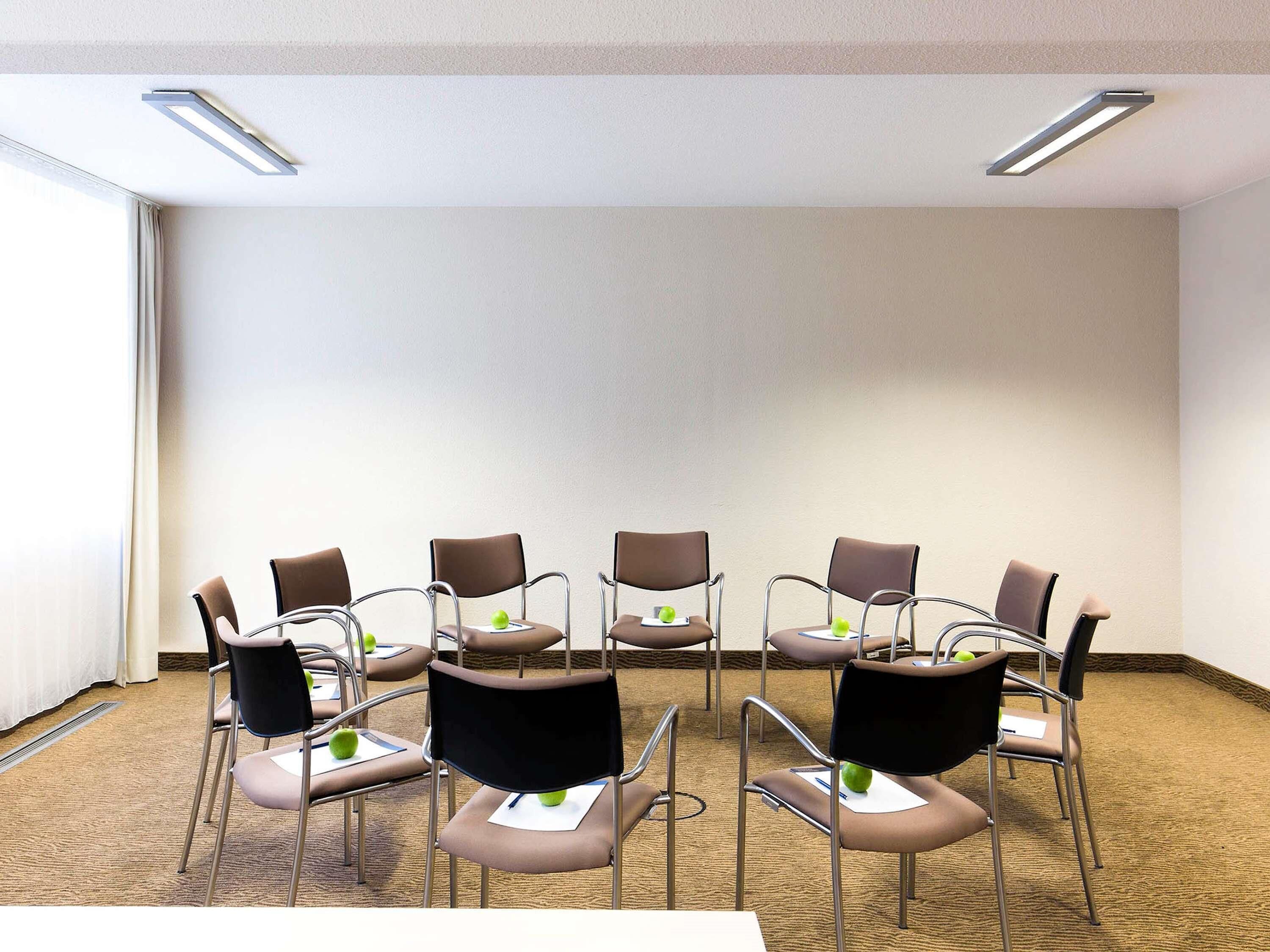 A conference room with a carpeted floor, white walls, and a plain backdrop.