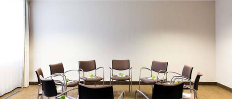 A conference room with a carpeted floor, white walls, and a plain backdrop.