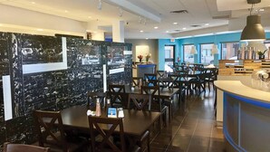 Un restaurant aux murs de marbre, aux tables en bois et dont un mur est peint en bleu.