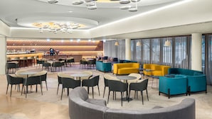 A modern hotel lobby with a bar area, seating arrangements, and a unique ceiling design. - Ensana Thermal Aqua (Hévíz)
