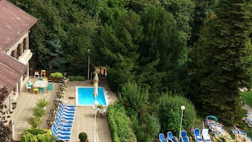 Ein Poolbereich auf dem Dach mit Liegestühlen, einem Schwimmbecken und umgebender Bepflanzung.