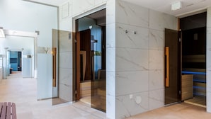 A modern lobby with marble walls, glass doors, and a wooden bench. - Ensana Thermal Aqua (Hévíz)