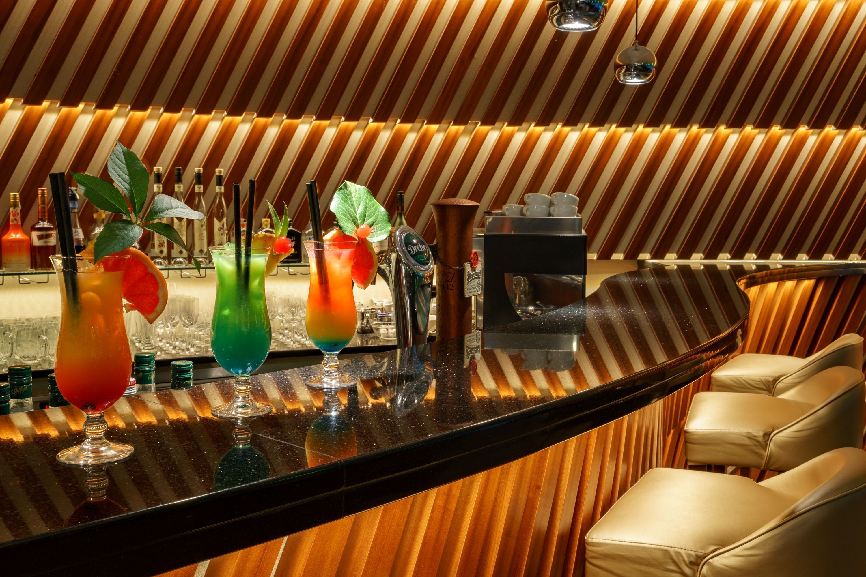 Un espace bar avec un mur en bois à rayures, une machine à café et des tabourets de bar.
