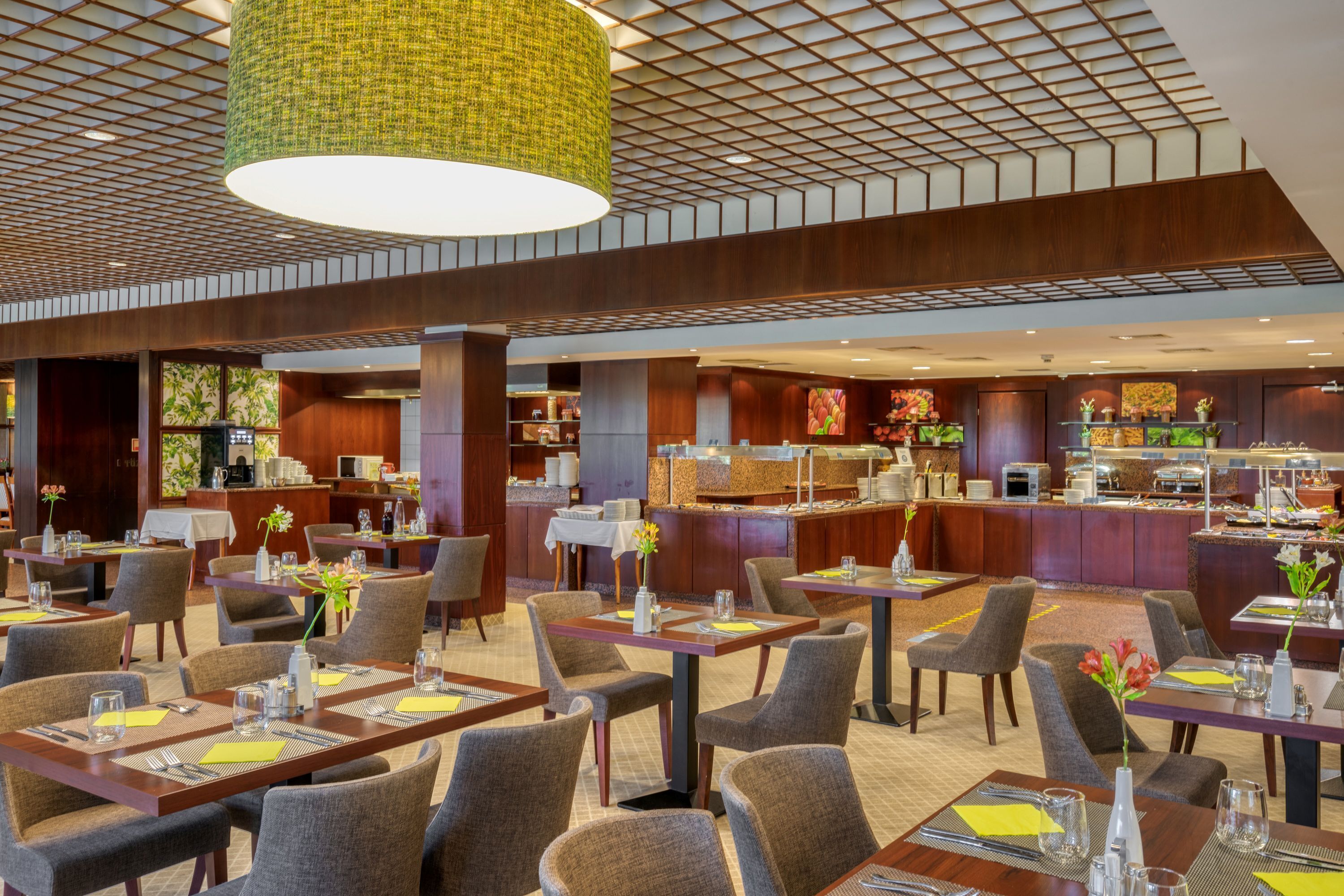A modern hotel lobby with a central bar area, dining tables, and chairs.