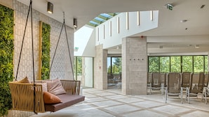 A modern interior with a hanging swing chair, a green wall, and a spacious seating area. - Ensana Thermal Aqua (Hévíz)