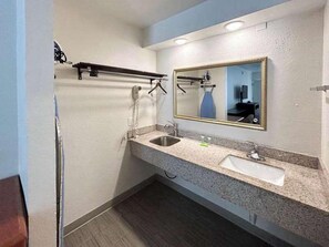 A modern bathroom with two sinks, a large mirror, and a towel rack. - Studio 6 Fort Worth, TX – Downtown East (Fort Worth)