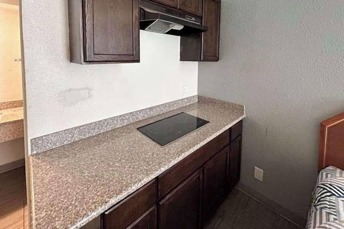 A kitchen with dark wooden cabinets, a granite countertop, and a built-in stove.